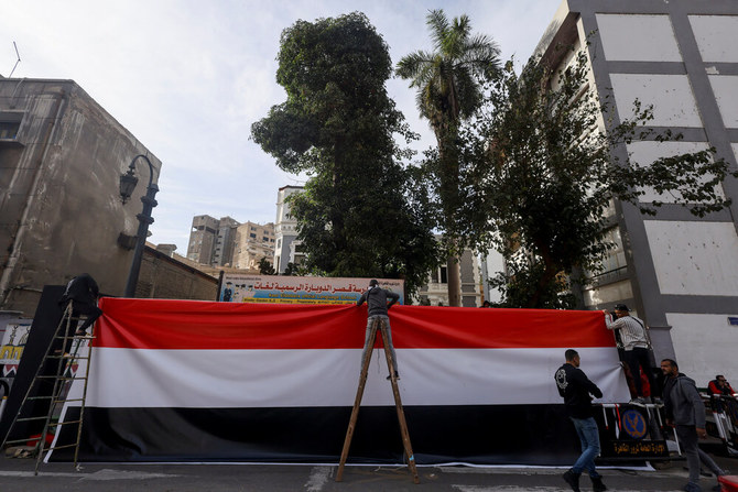 Workers place an Egyptian flag at the entrance of one of the schools that will be used as a polling station in the upcoming presidential elections, in Cairo on Dec. 9, 2023. (Reuters)