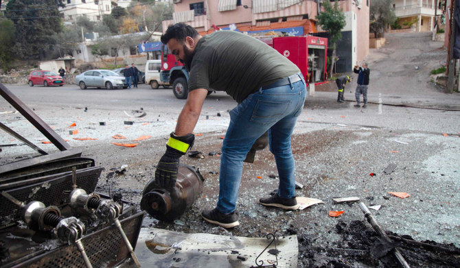 Emergency service members work at the site of Israeli shelling which hit a supermarket and a coffee shop in the southern Lebanese village of Adaysseh near the border with Israel on December 8, 2023, amid ongoing cross-border tensions as fighting continues with Hamas militants in the southern Gaza Strip. (AFP)