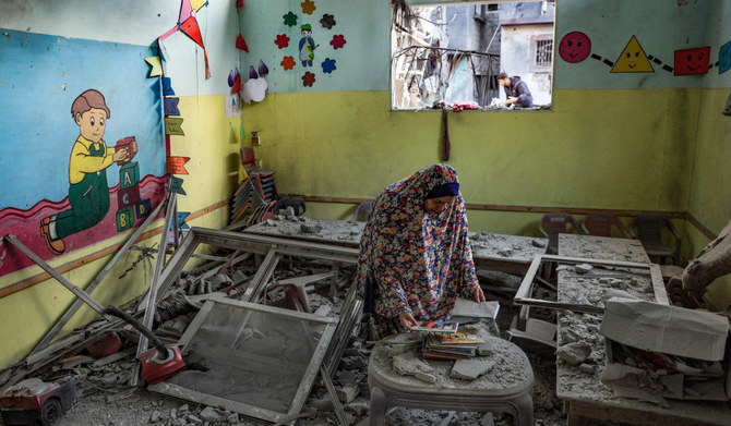 A woman tries to salvage some books inside a kindergarten hit by Israeli bombing in Rafah in the southern Gaza Strip on December 9, 2023, amid continuing battles between Israel and the militant group Hamas. (AFP)
