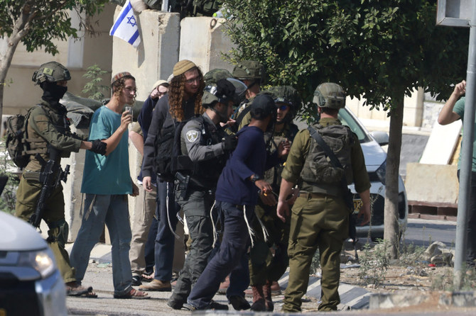 Israeli soldiers restrain Jewish settlers after they stormed the Palestinian West Bank village of Dayr Sharaf on November 2, 2023, amid the ongoing battles between Israel and Hamas in the Gaza Strip. (AFP/File)