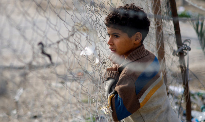 A boy looks through a fence as displaced Palestinians who fled their homes due to Israeli strikes shelter at Rafah crossing on the border with Egypt, amid the ongoing conflict between Israel and the Palestinian Islamist group Hamas, in Rafah in the southern Gaza Strip, December 8, 2023. (Reuters)