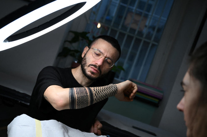 Palestinian Syrian poet Ramy Al-Asheq, 34, looks at his forearm which is tattoed with the black-and-white chequerboard pattern of the Palestinian keffiyeh (REUTERS)