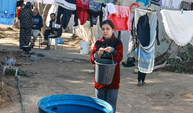 A girl carries a bucket of water at a camp for displaced Palestinians in Rafah in the southern Gaza Strip on Saturday amid continuing battles between Israel and Hamas. (AFP)