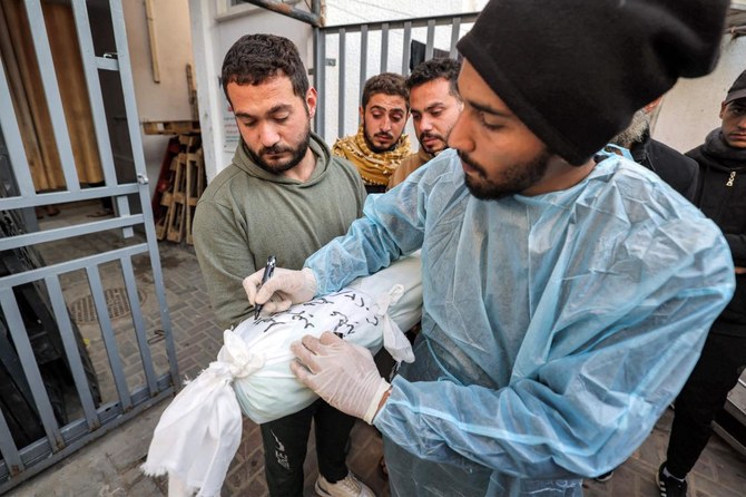 A hospital worker writes the name and information on the body of a Palestinian child who was killed overnight during Israeli bombardment, at a hospital in Rafah in the southern Gaza Strip on Dec. 19, 2023. (AFP)