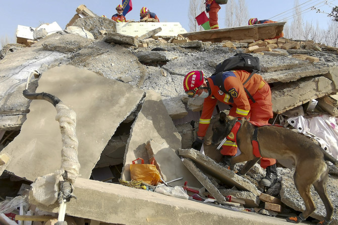 A rescuer uses a sniffer dog to search for survivors at a collapsed house in Linxia Hui Autonomous Prefecture, northwest China’s Gansu Province on Dec. 19, 2023. (Xinhua via AP)