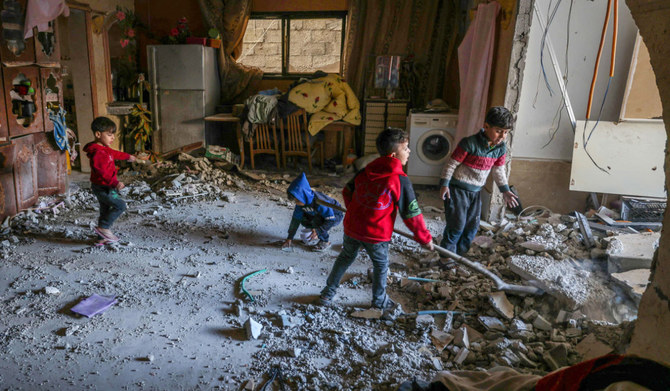 Palestinian children collect small pieces of debris following Israeli bombardment in Rafah in the southern Gaza Strip on December 22, 2023, amid continuing battles between Israel and the militant group Hamas. (AFP)