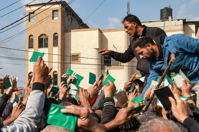 Palestinians wave their identity cards as they gather to receive flour rations for their families outside a warehouse of the United Nations Relief and Works Agency for Palestine Refugees (UNRWA) in Rafah. (File/AFP)