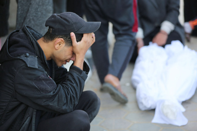 A Palestinian man reacts near the shrouded bodies of relatives killed following Israeli bombardment, at a hospital in Deir al-Balah in the central Gaza Strip on December 20, 2023, amid the ongoing conflict between Israel and the Palestinian militant group Hamas. (AFP)