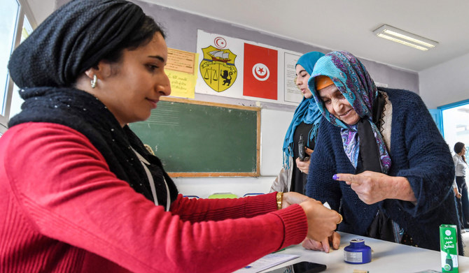 A voter is assisted to dip her finger in ink after voting at a polling station during the 2023 local elections in the locality of Mnihla in Ariana province on the outskirts of Tunis on December 24, 2023. (AFP)