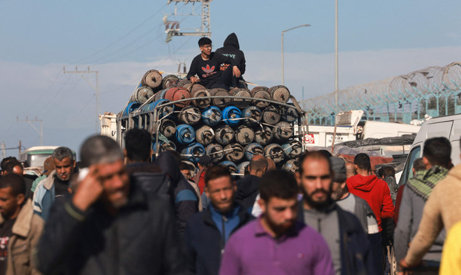 Palestinians collect empty gas containers to replace for displaced families near their makeshift shelters in Rafah in the southern Gaza Strip on December 24, 2023, amid continuing battles between Israel and the militant group Hamas. (AFP)