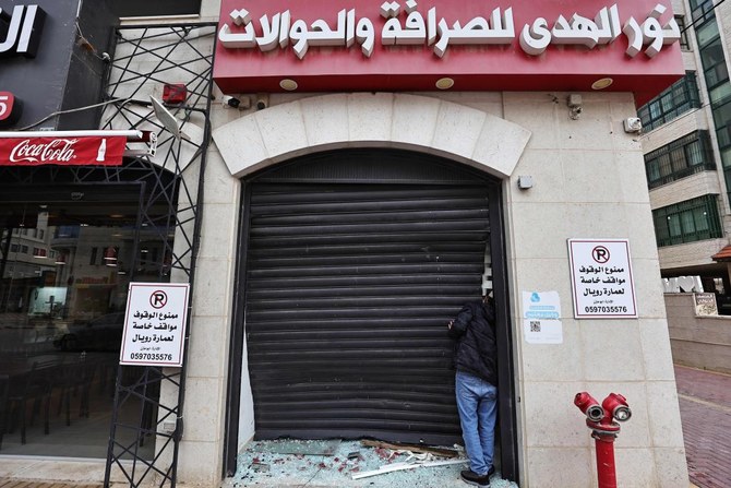 A Palestinian man inspects the damage to a money exchange shop, after a raid by the Israeli army, in the city of Ramallah in the occupied West Bank (AFP)