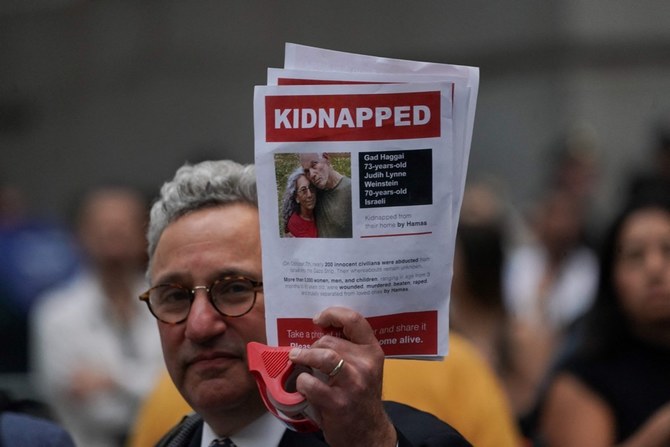A supporter of Israel holds a picture of kidnapped Israeli hostages Gad Haggai and Judith Weinstein Haggai. (AFP)