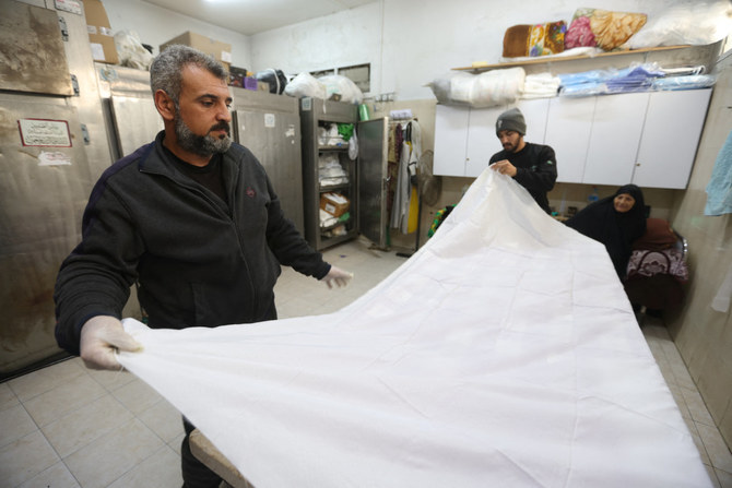 Mohammed Abu Mussa, a volunteer at Keratan society which prepares dead bodies for burial, prepares a white shroud at a hospital in Rafah, southern Gaza Strip, on Dec. 28, 2023. (REUTERS/Ibraheem Abu Mustafa)