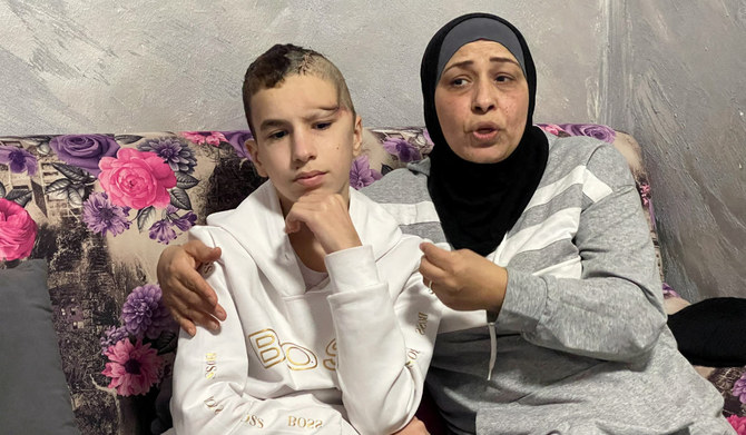 14-year old Palestinian Abdelrahman Zaghal, who was released from Israeli detention after a hostages-prisoners swap deal between Hamas and Israel, sits next to his mother Najah as she talks in their house in Jerusalem, December 6, 2023. (REUTERS)