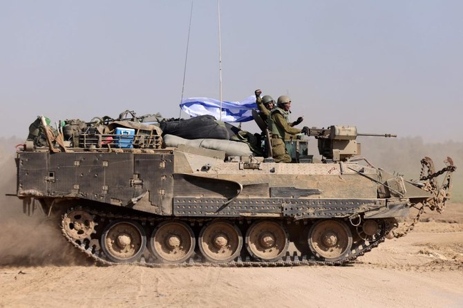 Israeli soldiers on an armoured personnel carrier (APC) waving an Israeli flag as they roll back from the Gaza Strip, amid continuing battles between Israel and the militant group Hamas. (AFP)