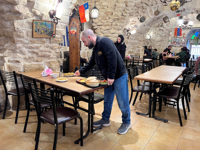 Fourth generation co-owner of Restaurant Afteem, Ala'a Salameh, 42, places food on a table inside the restaurant in Bethlehem, in the Israeli occupied West Bank, December 9, 2023. (Reuters)