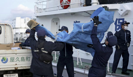 The members of Japanese Coast Guard carry the debris which are believed to be from the crashed US military Osprey aircraft, at a port in Yakushima, Kagoshima prefecture, southern Japan, Monday, Dec. 4, 2023. (Kyodo News via AP)