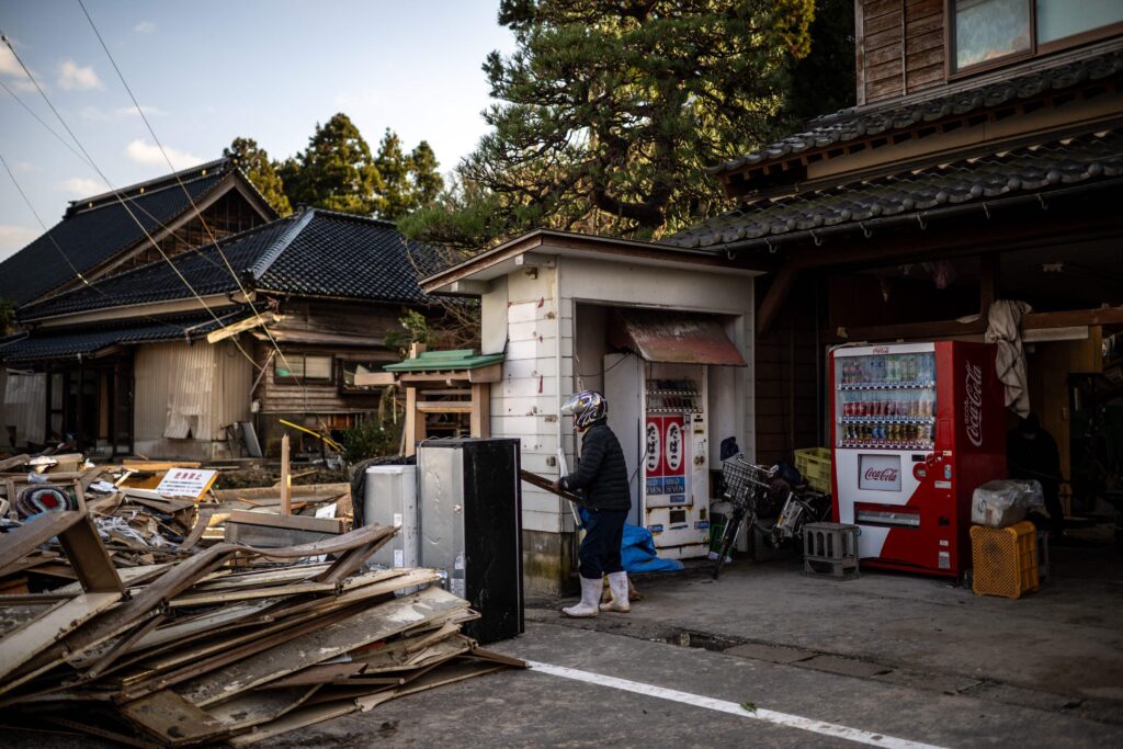 A man cleans his house in Shiromaru, Ishikawa prefecture on January 5, 2024, after a major 7.5 magnitude earthquake struck the Noto region in Ishikawa prefecture on New Year's Day. (Photo by Philip FONG / AFP)