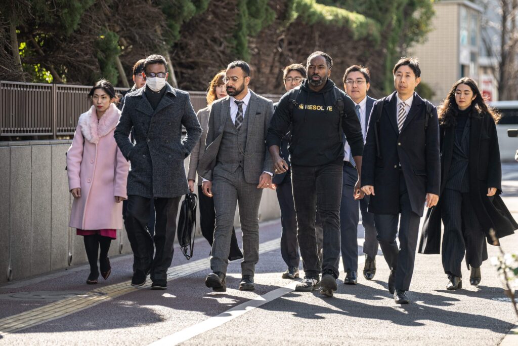 Matthew (first name only), a Pacific Islander with Japanese permanent residency status (front L,) Syed Zain, a Japanese citizen with Pakistani origin (front C) and Maurice (first name only), a US citizen with Japanese permanent residency status (front 2nd R), walk outside the Tokyo District Court in Tokyo on January 29, 2024. (Photo by Philip FONG / AFP)