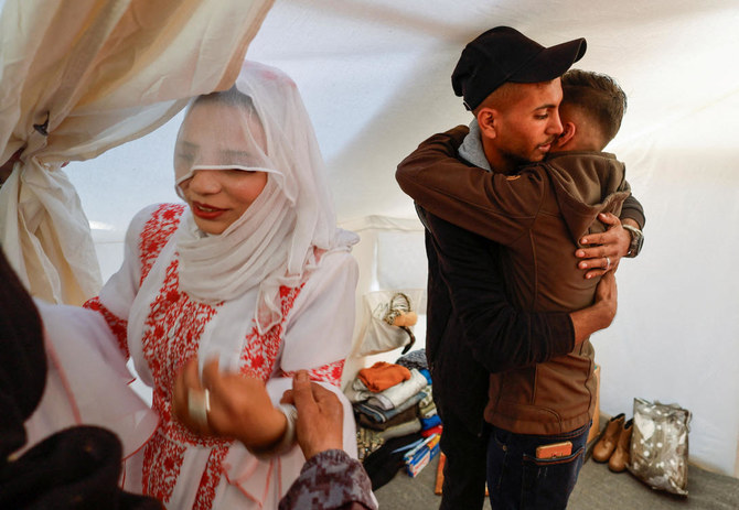 A Palestinian couple, Mohammed Al-Ghandour and his bride Shahad, greet guests in a tent camp, amid the ongoing conflict between Israel and Hamas, on their wedding day, in Rafah on Jan. 18, 2024. (Reuters)