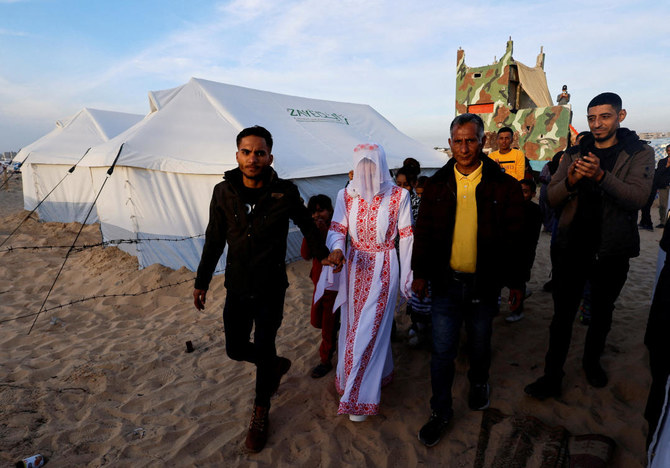 A Palestinian couple, Mohammed Al-Ghandour and his bride Shahad, walks on their wedding day in the tent camp, amid the ongoing conflict between Israel and Hamas, in Rafah on Jan. 18, 2024. (Reuters)