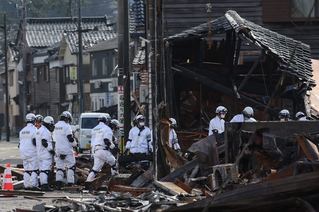 Gunma prefectural police officers work near the ruins of the popular shopping area which was destroyed by fire in the disaster-hit city of Wajima, Ishikawa prefecture on January 11, 2024. (AFP)