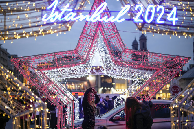 A woman, poses for photographs next to Luminous shapes in central Istanbul's Taksim Square, in Istanbul, Turkiye, on Dec. 31, 2023. (AP)