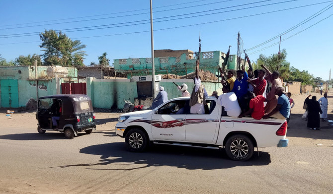 Armed Sudanese civilians wave weapons and chant slogans as they drive through the streets of Gedaref city in eastern Sudan on January 1, 2024 to express their support for the Army. (AFP)