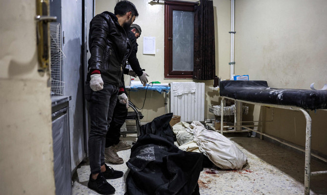 Men stand over the bodies of two victims who were killed in the aftermath of reported bombardment by Syrian government forces, at a hospital in the rebel-held city of Idlib in northwestern Syria on December 30, 2023. (AFP)