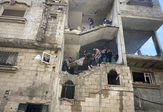 Palestinians carry the dead body of a woman casualty in an Israeli strike on a house at Maghazi refugee camp in the central Gaza Strip on January 3, 2024. (REUTERS)