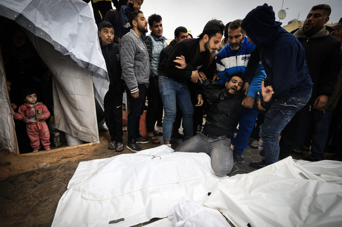 Displaced Palestinian children watch from inside a tent as a man mourns relatives killed in an overnight Israeli strike on the Al-Maghazi refugee camp on December 25, 2023. (AFP)