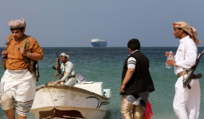 Armed men stand on the beach as the Galaxy Leader commercial ship, seized by Yemen's Houthis last month, is anchored off the coast of al-Salif, Yemen, December 5, 2023. (REUTERS)