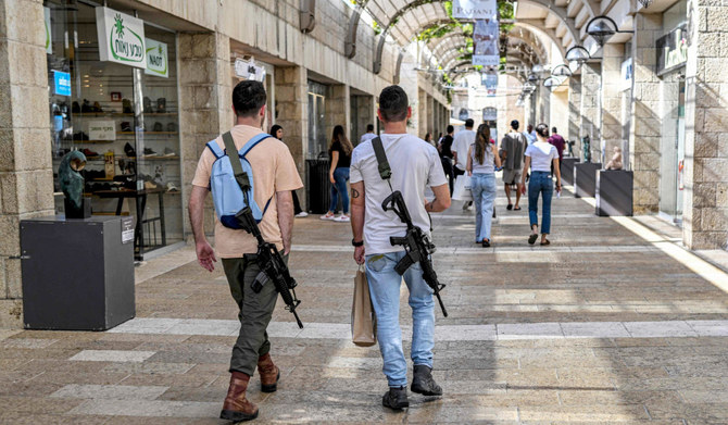 Off duty Israeli soldiers carrying US-made M16 automatic assault rifles, walk in a shopping centre in Jerusalem on October 25, 2023, amid the ongoing battles in the Gaza Strip between Israel and the Palestinian group Hamas. (AFP)