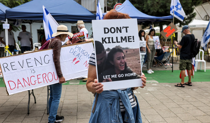 A woman stands holding a sign showing Israeli student Noa Argamani, one of the Israeli hostages held by Palestinian militants since the October 7 attacka, during a demonstration near Azrieli Mall in Tel Aviv on October 18, 2023. (AFP)