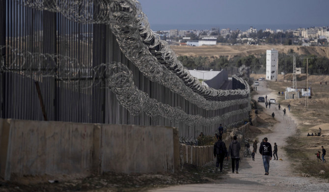 Palestinians displaced by the Israeli bombardment of the Gaza Strip walk next to the border with Egypt, in Rafah, southern Gaza, Jan. 14, 2024. (AP)