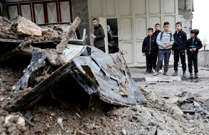 A Palestinian man and children inspect the site of an Israeli strike on a car in Nablus, in the Israeli-occupied West Bank. (Reuters)