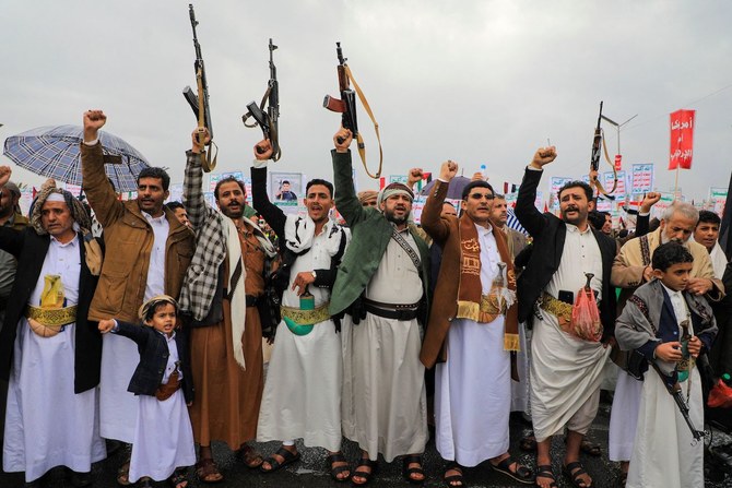 People lift rifles and placards as they chant during a Houthi rally in Sanaa on January 19, 2024. (AFP)