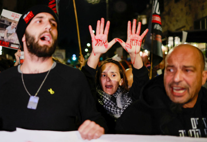 A demonstrator holds up their hands painted in red with the message