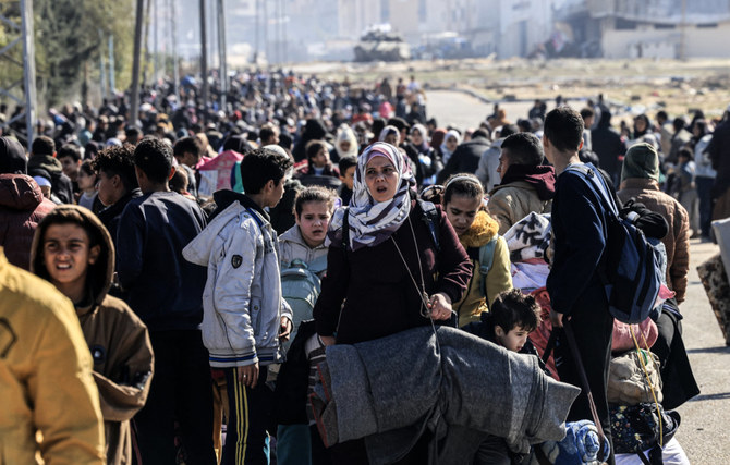 Palestinians carry some belongings as they flee Khan Younis to safer areas in the southern Gaza Strip through on January 26, 2024, amid continuing Israeli bombardment. (AFP)