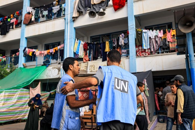 Workers of the United Nations Relief and Works Agency for Palestine Refugees (UNRWA) agency talk together in the playground of an UNRWA-run school that has been converted into a shelter for displaced Palestinians in Khan Yunis (AFP)