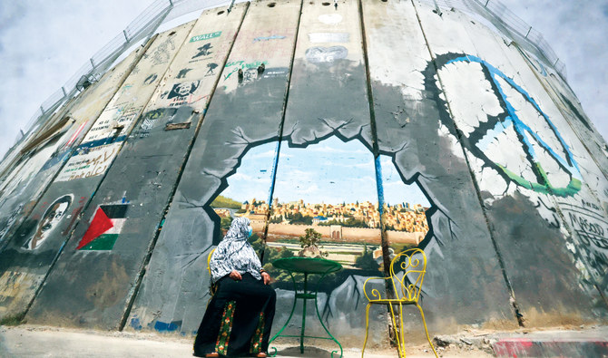 A Palestinian woman looks at a mural depicting Al-Aqsa Mosque compound and Jerusalem’s old city on Israel’s controversial separation barrier between Jerusalem and the occupied West Bank, in Bethlehem on April 17,2022. (AFP)