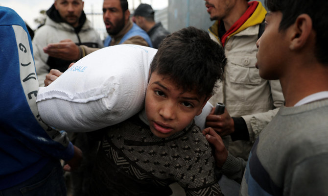 A Palestinian boy carries a bag of flour distributed by the United Nations Relief and Works Agency (UNRWA), amid the ongoing conflict between Israel and Hamas, in Rafah in the southern Gaza Strip January 29, 2024. (Reuters)