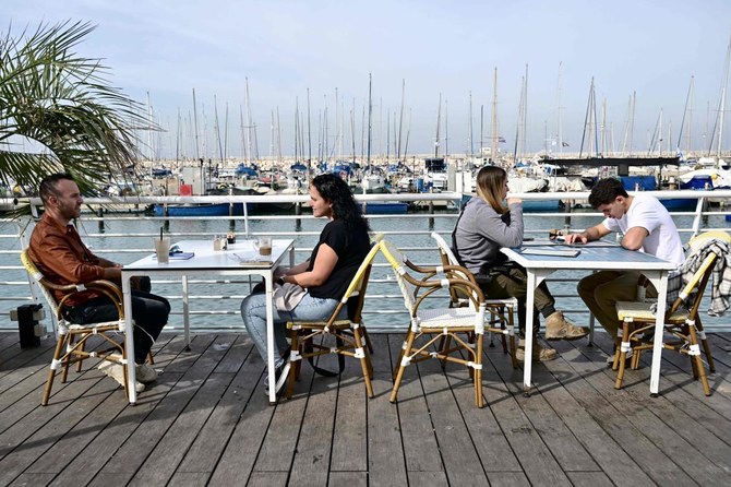 People sit at a bar at the marina in the Israeli coastal city of Ashkelon on Jan. 8, 2024, amid continuing battles between Israel and Hamas in Gaza Strip. (AFP)