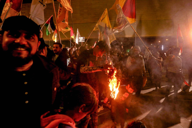 Supporters of pro-Iran factions wave various flags in Baghdad's Tahrir square on January 13, 2024. (AFP)