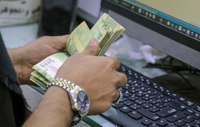 A cashier counts Yemeni riyal banknotes at a local currency exchange in Aden, Yemen, June 29, 2021. (Reuters)