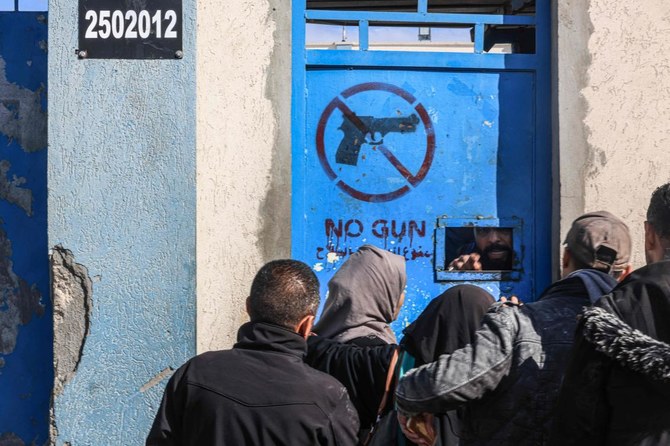 Displaced Palestinians queue to receive aid in front of the United Nations Relief and Works Agency for Palestine Refugees (UNRWA) center in Rafah in the southern Gaza Strip on January 28, 2024, amid ongoing battles between Israel and the Palestinian militant group Hamas. (AFP)