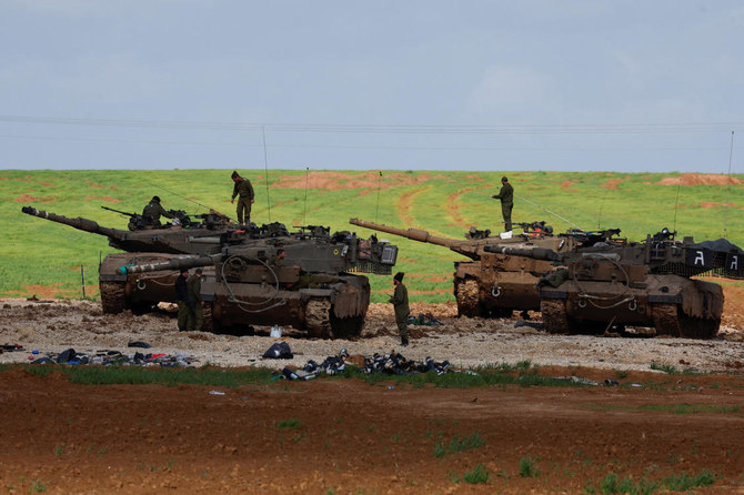 Israeli soldiers work on top of their tanks, amid the ongoing conflict between Israel and Hamas, near the northern Gaza border in Israel, on Jan. 30, 2024. (Reuters)