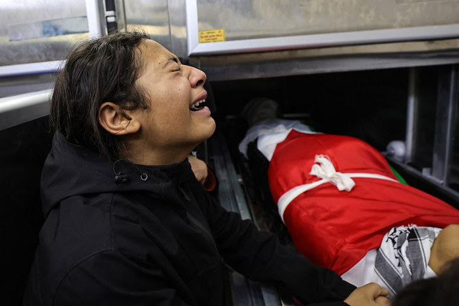 A child mourns over the body of one of five people killed by Israeli forces in the occupied West Bank city of Jenin during an overnight incursion. (File/AFP)