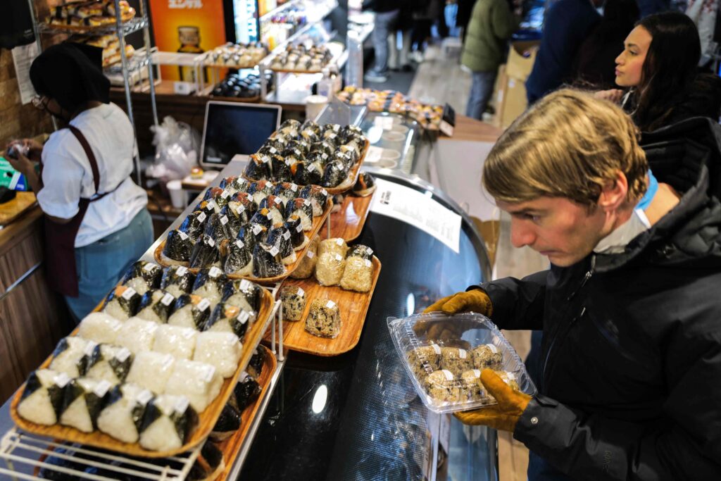 This picture taken on December 20, 2023 shows a customer buying rice balls, known as 