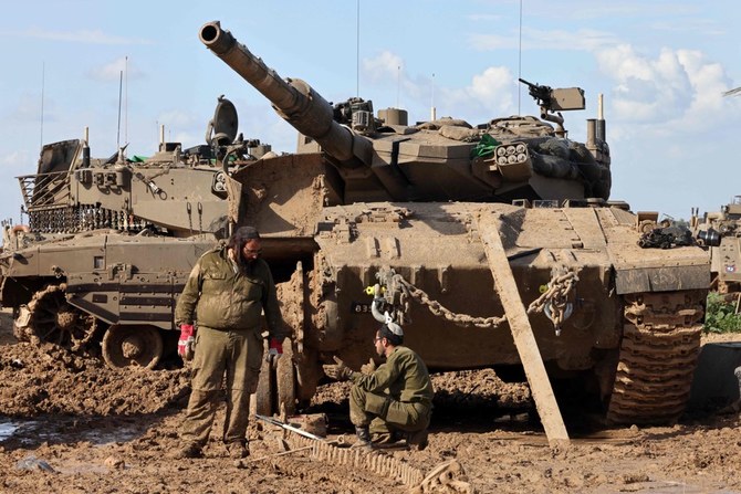 Israeli soldiers clean tank chains at a position near the border with the Gaza Strip, upon returning from a mission there on February 1, 2024, amid ongoing battles between Israel and the Palestinian militant group Hamas. (AFP)